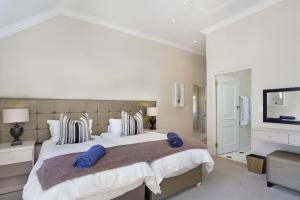a large white bedroom with a large bed with blue pillows at Winelands Golf Lodges 16 in Stellenbosch