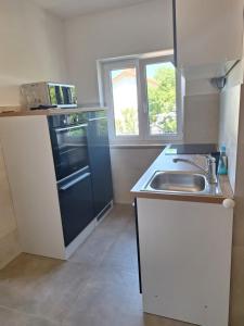a small kitchen with a sink and a stove at Apartmani Mia in Jadranovo