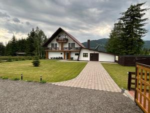 a large white house with a gambrel roof at Pensiunea Teodora in Dorna Arini
