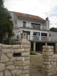 a large white house with a stone wall at Apartment Doderovic in Kostrena