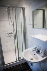uma casa de banho branca com um lavatório e um chuveiro em UtrechtCityApartments – Huizingalaan em Utrecht