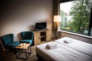 een hotelkamer met een bed en twee stoelen en een televisie bij UtrechtCityApartments – Huizingalaan in Utrecht