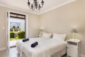 two beds in a white bedroom with a window at Winelands Golf Lodges 19 in Stellenbosch +31 photos