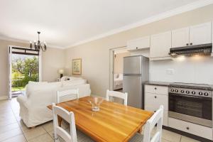 a kitchen and living room with a wooden table and chairs at Winelands Golf Lodges 19 in Stellenbosch