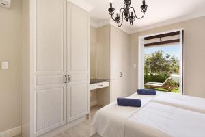 a white bedroom with a bed and a window at Winelands Golf Lodges 19 in Stellenbosch