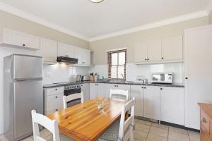 a kitchen with white cabinets and a wooden table at Winelands Golf Lodges 19 in Stellenbosch