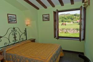 a bedroom with a bed and a horse outside a window at Posada La Roblera in Oreña