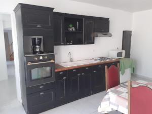 a kitchen with black cabinets and a sink and a stove at Gites Domaine de Sweendy in Le Bugue