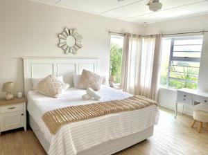 a white bedroom with a large bed and a window at The Golf Shack in Port Alfred