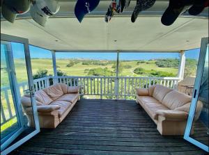 a screened in porch with couches on a deck at The Golf Shack in Port Alfred +8 photos