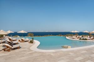a large swimming pool with chairs and umbrellas at Vione Paros in Ambelas