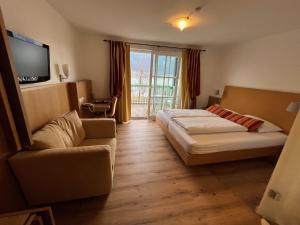 ein Hotelzimmer mit einem Bett und einer Couch in der Unterkunft Seehotel Hoffmann in Steindorf am Ossiacher See + 65 Fotos