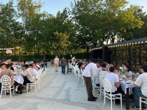 Eine Gruppe von Menschen sitzt an Tischen in einem Garten in der Unterkunft Odamarani in Kutaissi