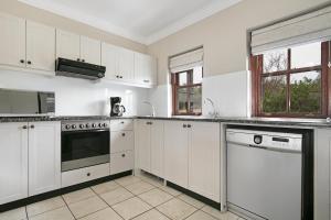 une cuisine blanche avec des armoires et des appareils blancs dans l'établissement Winelands Golf Lodges 26, à Stellenbosch