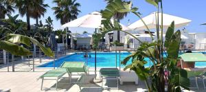 - une piscine avec des chaises longues et des parasols à côté d'un complexe dans l'établissement Sea Home Sunrise, à Tortoreto Lido