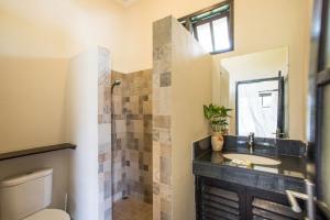 Un baño con lavabo, inodoro y espejo. en Villa Rumah Rindu, en Lovina 12 fotos más