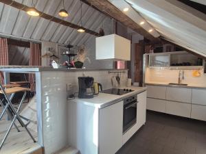 a kitchen with white cabinets and a stove top oven at Lägenhet-vindsvåning i centrala öregrund in Öregrund