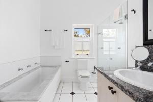 a bathroom with a tub and a toilet and a sink at Winelands Golf Lodges 28 in Stellenbosch
