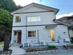 a house with two chairs and a patio in front of it at はなの環 in Nikko