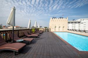 a deck with chairs and a swimming pool on a building at Dewan Bangkok in Bangkok