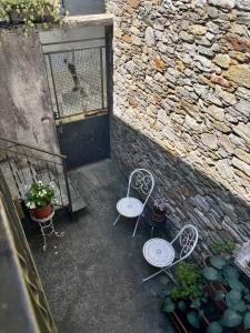 zwei Stühle und eine Bank neben einer Steinmauer in der Unterkunft La casina del lago vicino al bosco in Ghiffa