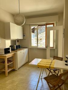 eine Küche mit weißen Schränken und einem Tisch mit Stühlen in der Unterkunft La casina del lago vicino al bosco in Ghiffa