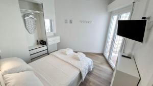 Dieses weiße Zimmer verfügt über 2 Betten und einen Flachbild-TV. in der Unterkunft Casa Sardina in San Benedetto del Tronto