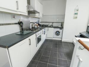 a kitchen with white cabinets and a tile floor at Lady of the Lake Suite in Holyhead