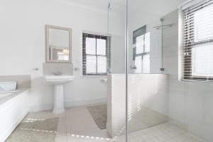 a white bathroom with a shower and a sink at Winelands Golf Lodges 33 in Stellenbosch