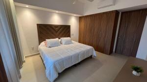 a bedroom with a white bed with a wooden headboard at Departamento TerraMar Flamingos in Nuevo Vallarta +33 photos
