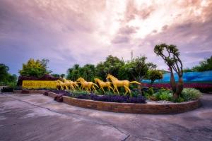 a statue of galloping horses in a garden at Thansila Resort&Garden Buriram in Buriram