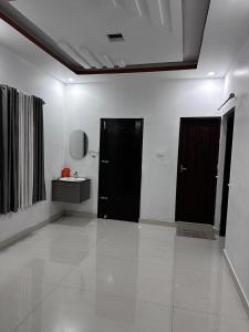 a white room with two black doors and a sink at Yatri Haven Varkala in Varkala