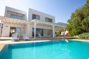 a villa with a swimming pool in front of a house at Bitter Orange Villa with Pool by HolidayKeys in Kérynia