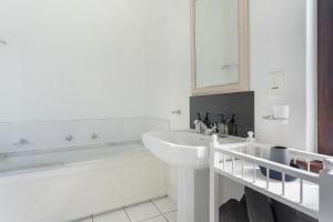 a white bathroom with a sink and a mirror at Winelands Golf Lodges 39 in Stellenbosch