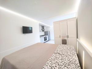 une chambre blanche avec un lit et une télévision au mur dans l'établissement Il Posticino House in Marina, Garden and Veranda, à Marina di Massa