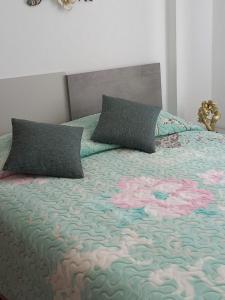a bed with two pillows on top of it at Aurora's Apartment Shkoder in Shkodër