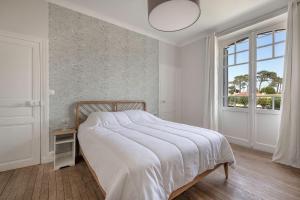 a white bedroom with a bed and a window at Villa de charme classée à Tharon Plage pour 14 in Tharon-Plage