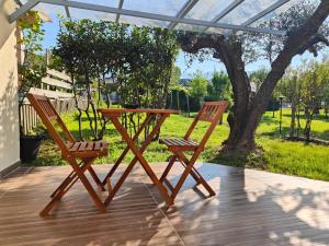 deux chaises en bois et une table sur une terrasse dans l'établissement Il Posticino House in Marina, Garden and Veranda, à Marina di Massa