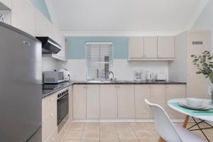 a kitchen with white cabinets and a table at Winelands Golf Lodges 40 in Stellenbosch