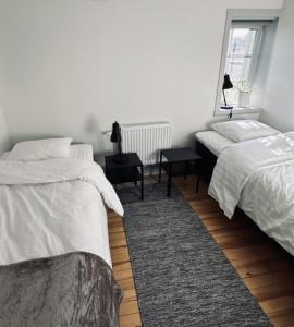 a white bedroom with two beds and a window at Litet hus nära Värnamo 