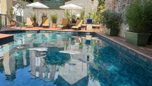 a swimming pool with chairs and umbrellas at Logis Hôtel Restaurant Grand Hôtel de Lyon in Vals-les-Bains
