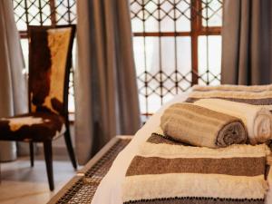 two beds with towels and a chair in a room at Kudu Kopje Lodge in Kroondal