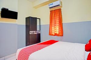 a bedroom with a bed with an orange curtain at Dancenter Juma Ciger Hotel Medan in Medan