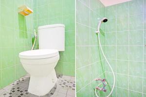 a bathroom with a toilet in a green tiled wall at Dancenter Juma Ciger Hotel Medan in Medan