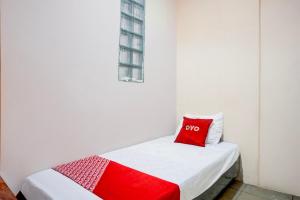 a small white room with a red pillow on a bed at Dancenter Waringin Residence in Medan