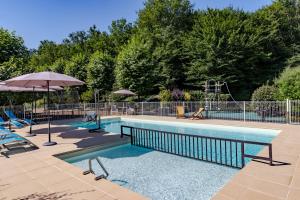 piscina con ombrellone e sedie e ombrellone di Maison Rose a Castelnaud-la-Chapelle