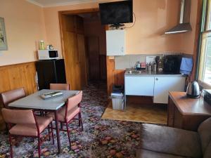a living room with a table and a kitchen at Snug as a Bug Omeo in Omeo