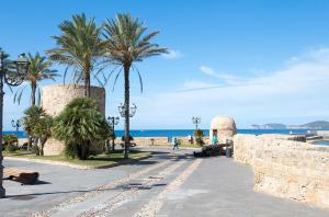 Una acera con palmeras y el océano al fondo en Villa Marina, en Alghero