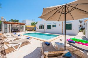 a swimming pool with chairs and an umbrella at Casa Carmela in Cacla D'or