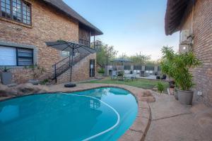 a swimming pool in front of a building with an umbrella at Stay at Royal in Marloth Park